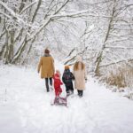 a family walking in the snow covered forest